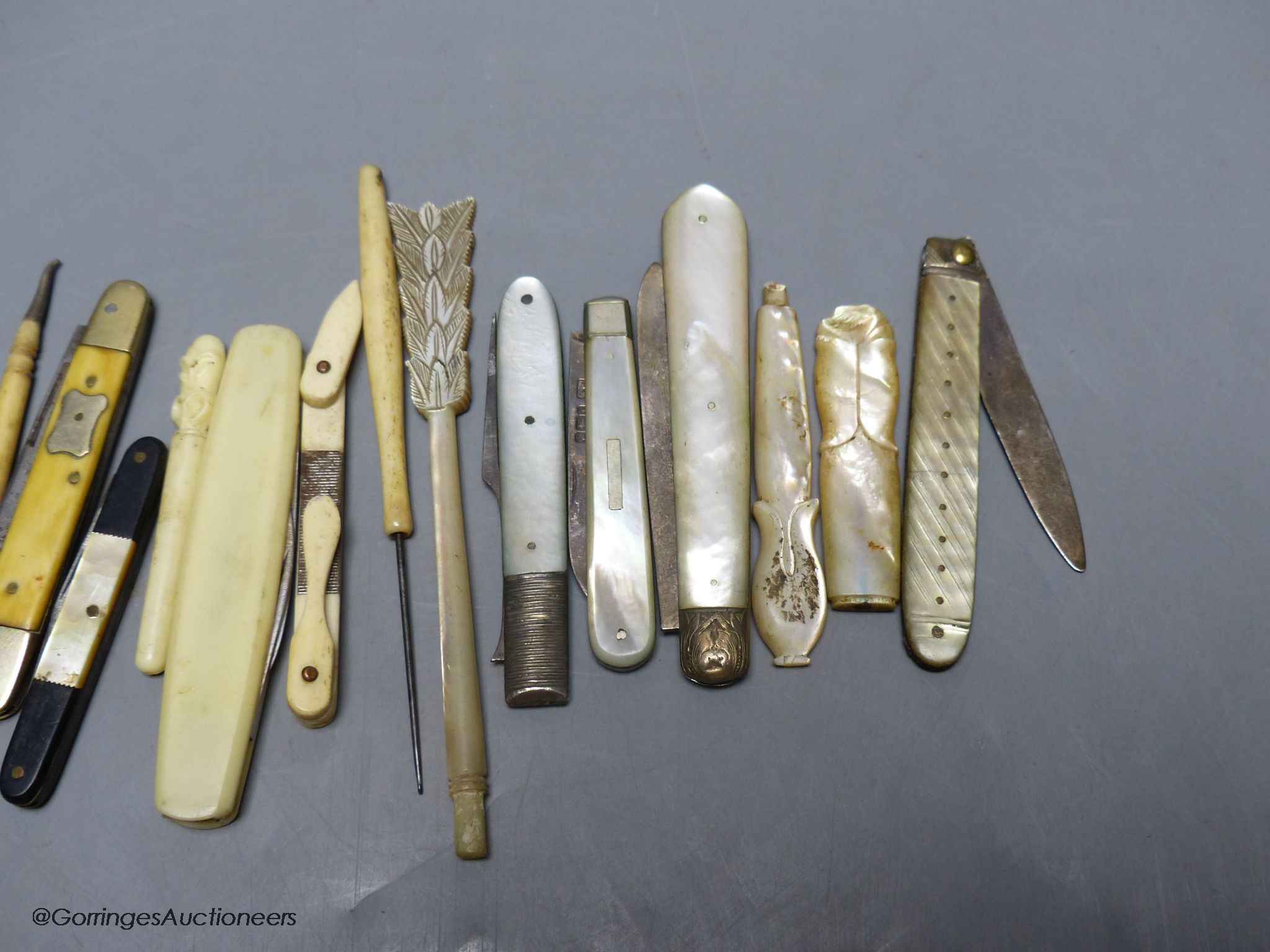 A group of silver and steel bladed pocket folding knives and a fork